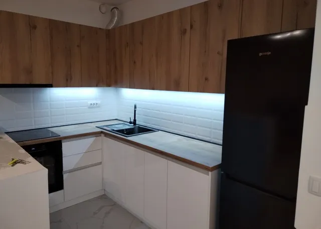 Detalj iste kuhinje — ugao sa sudoperom i LED osvetljenjem ispod gornjih elemenata
